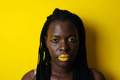 Close-up portrait of woman against yellow background