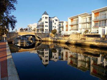 Reflection of buildings in city against clear sky