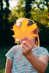 Midsection of woman holding maple leaves during autumn