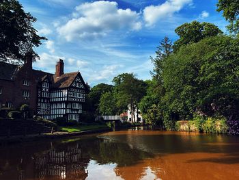 Reflection of trees and buildings in lake against sky