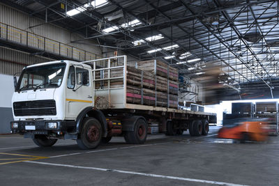 Forklift loading crates on parked truck in warehouse