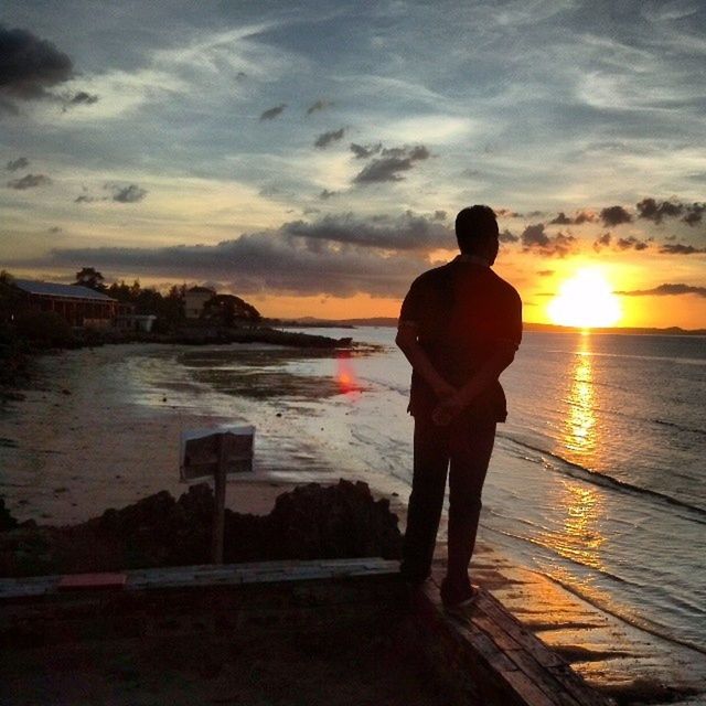 sunset, water, lifestyles, sky, leisure activity, full length, silhouette, rear view, sea, standing, cloud - sky, men, beauty in nature, orange color, sun, scenics, person, tranquil scene