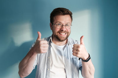 Portrait of young man gesturing against blue background