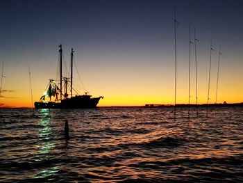 Sailboats sailing in sea against sky during sunset