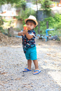 Cute boy holding toy gun standing outdoors