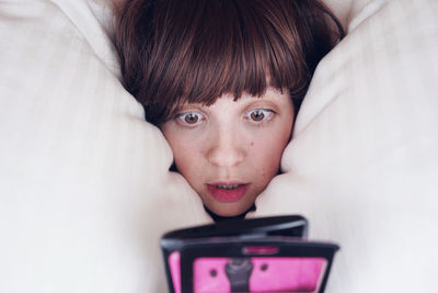 High angle view of shocked woman on bed at home