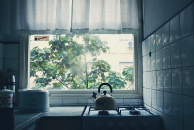 Teapot on stove by window at home