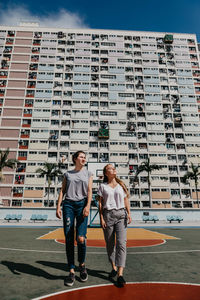 Friends walking against buildings in city