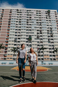 Full length of people walking against buildings in city