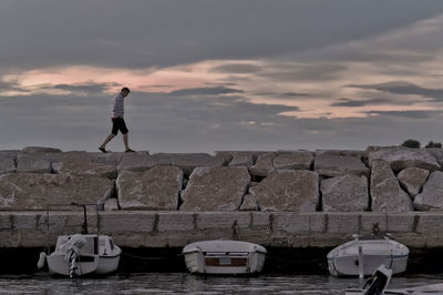 Man standing by sea against sky during sunset