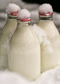 Close-up of milk bottles on snow covered field during winter