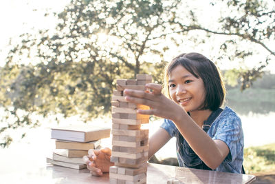 Smiling girl building wooden blocks in park