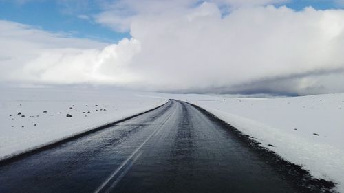 Road amidst snow against sky during winter