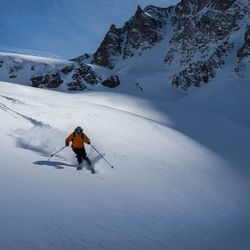 Man skiing on snow covered mountain against sky