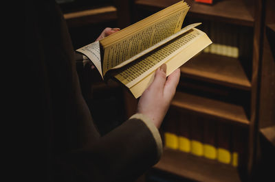 Midsection of woman holding book in library