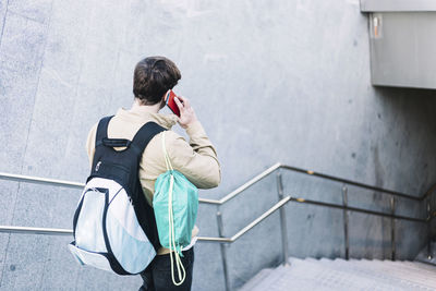 High angle view of young man using smart phone while moving down steps