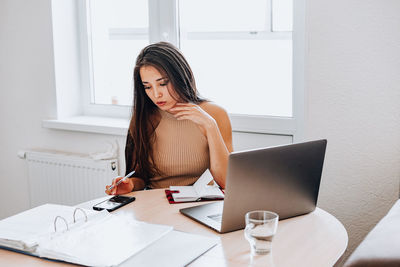 Woman using phone while sitting on table