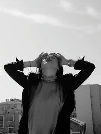 Woman having headache while standing against sky