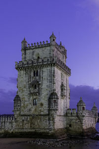 Low angle view of historic building called torre de belém in front of tejo river against sky