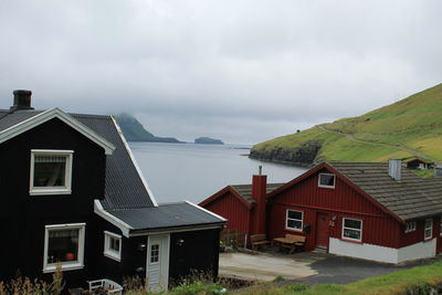 Houses by sea against sky