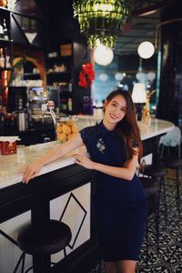 Portrait of young woman standing in restaurant