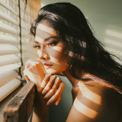 Close-up of thoughtful woman looking through window at home