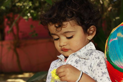 Close-up portrait photo of a small indian asian little boy holding maize fruits , india