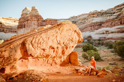 Woman sits at epic campsite under red rock in the maze utah