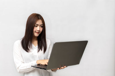Young woman using mobile phone against white background