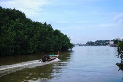 Man in boat sailing on river against sky