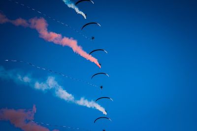 Low angle view of birds flying against blue sky