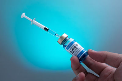 Close-up of person hand against blue wall