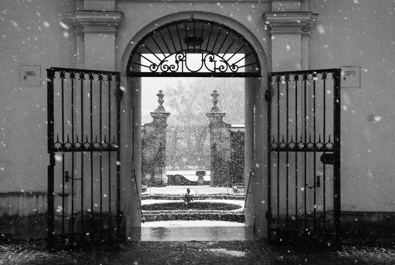 architecture, black and white, gate, built structure, entrance, monochrome, monochrome photography, building, black, building exterior, closed, door, no people, day, arch, white, outdoors, iron, window, the past, history, nature, religion, security