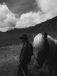 Man with horse on mountain against sky