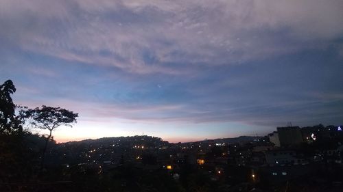 Illuminated buildings in city against sky at sunset