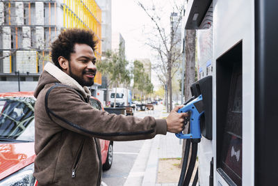 Afro man holding electric pump at charging station
