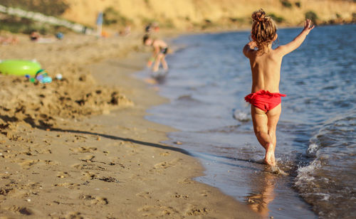 Rear view of shirtless man standing on beach