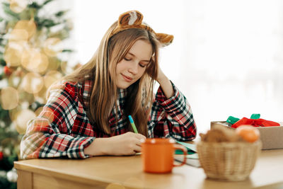 A charming girl in tiger ears writes wishes for christmas or new year. preparation for the holiday