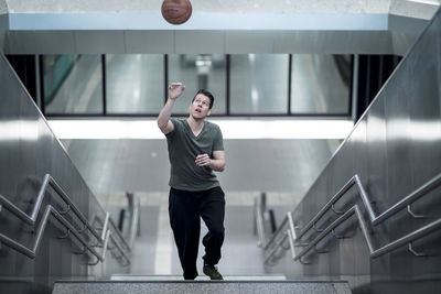 High angle view of young man playing with basketball moving up on steps