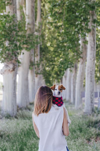 Rear view of woman with dog standing against plants