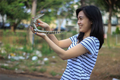 Side view of young woman holding sunglasses on land