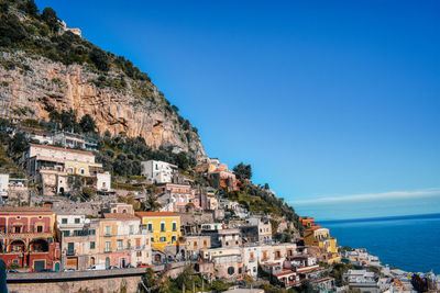 Townscape by sea against clear blue sky