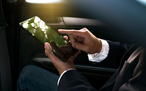 Midsection of man holding camera in car