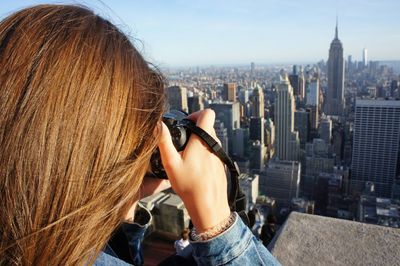 Rear view of woman photographing cityscape