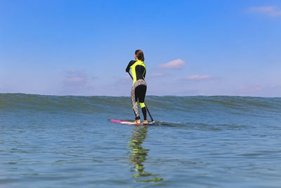 Rear view of woman in sea against sky