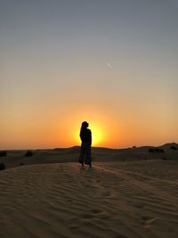 Silhouette man standing on beach against sky during sunset