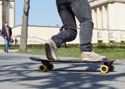 Low section of man skateboarding on road