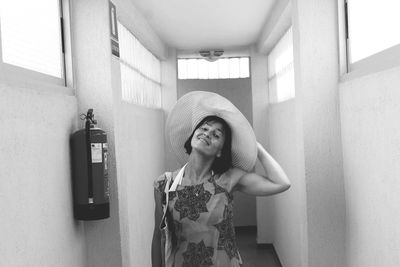 Portrait of young woman wearing hat while standing in corridor