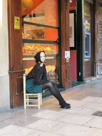 Full length of woman sitting on chair outdoors