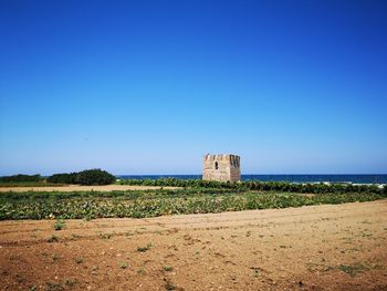 Built structure on field against clear blue sky